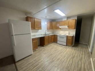 A kitchen with white appliances and wooden cabinets.