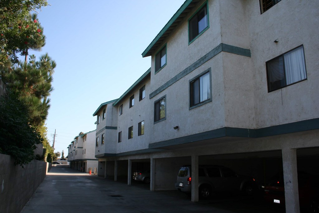 A street view of a residential area with apartment buildings and cars parked in the garage.