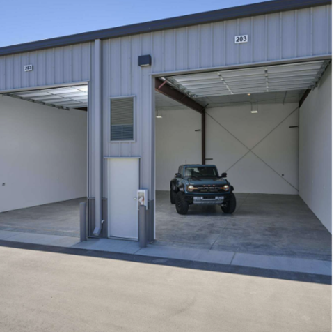 A black jeep is parked in a garage with a white door.