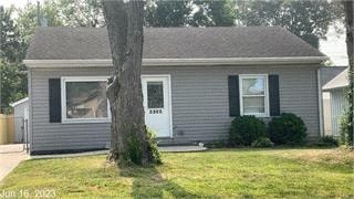 A small house with a white door and a tree in front.