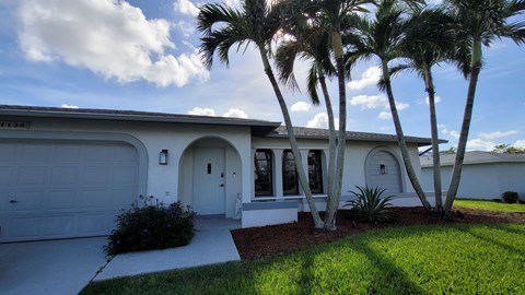 A white house with a garage door and a driveway.