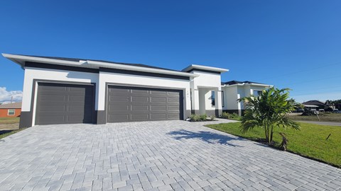 A modern house with a grey driveway and two garages.