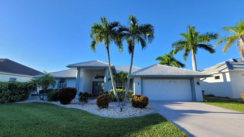 A house with a white fence and a palm tree in front.