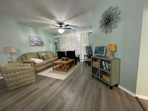 A living room with a ceiling fan and a painting on the wall.