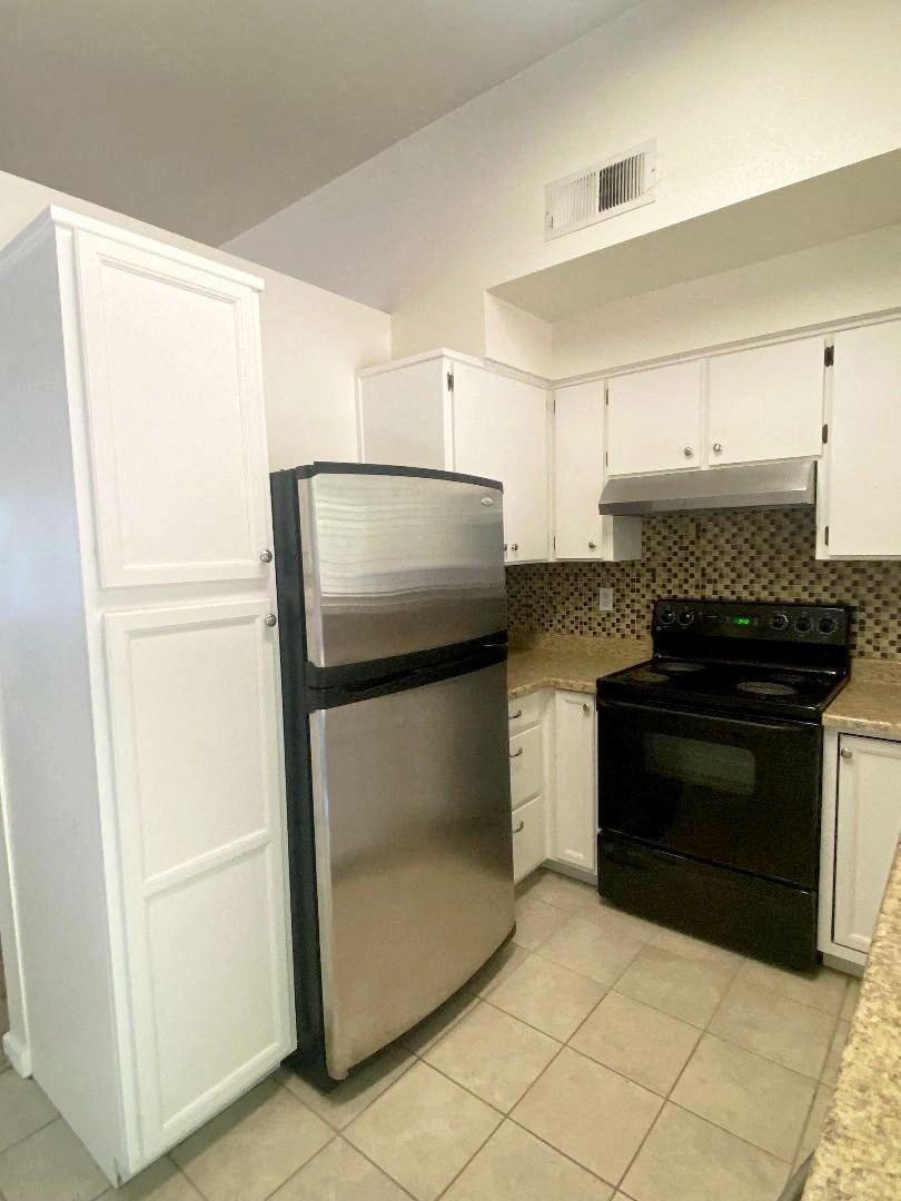 A kitchen with a black stove and white cabinets.