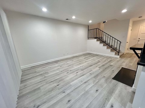 A room with a wooden floor and a staircase.