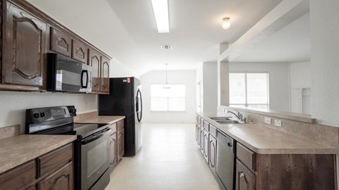 A kitchen with dark wood cabinets and black appliances.