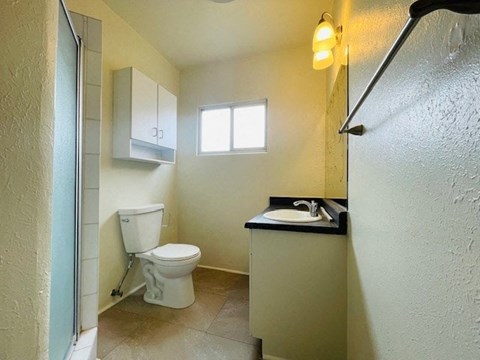 A small bathroom with a toilet, sink, and window.