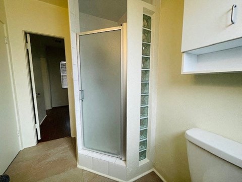 A white bathroom with a glass shower door and a white bathtub.