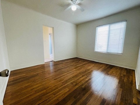 A room with wooden flooring and a ceiling fan.