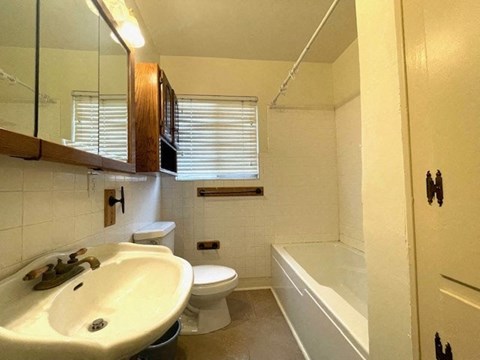 A bathroom with a white toilet, sink, and bathtub.