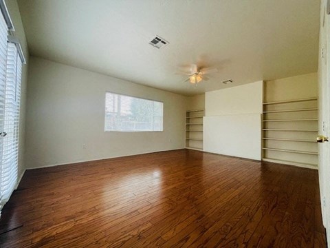 A room with wooden floors and a window with blinds.