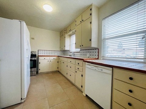 A kitchen with white appliances and cabinets.