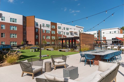 A patio with chairs and a table is surrounded by a brick building.
