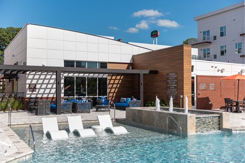 A pool area with a water feature and lounge chairs.