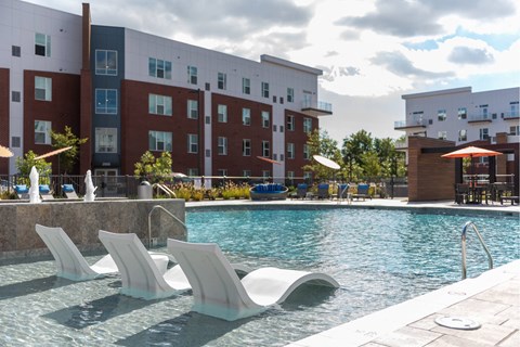 A pool with sun loungers in front of a building.