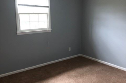 A room with a window and carpeted floor.