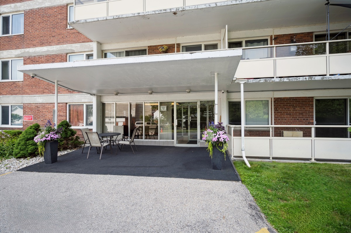 A white building with a balcony and a gravel driveway.