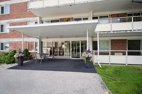 A white building with a balcony and a gravel driveway.