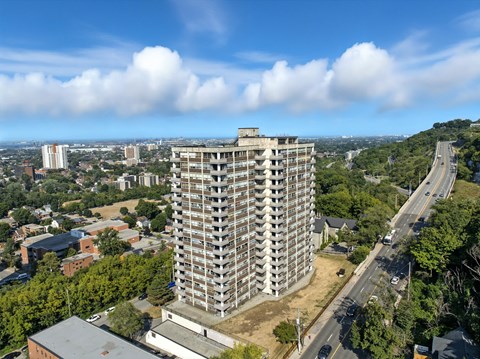 A tall building with many windows is surrounded by trees and other buildings.