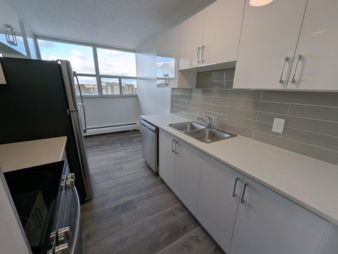 A kitchen with white cabinets and a black refrigerator.