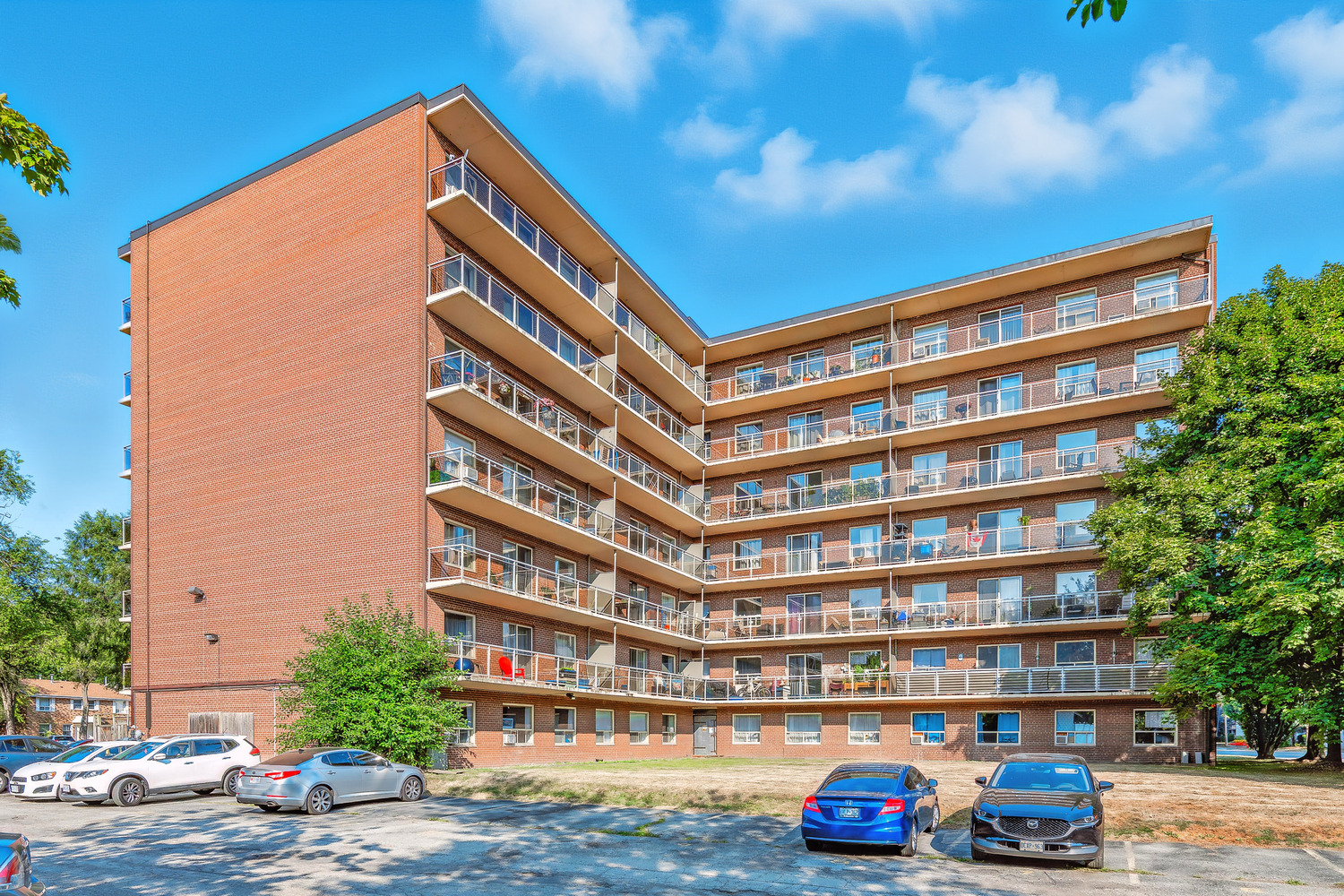 A large apartment building with a parking lot in front.