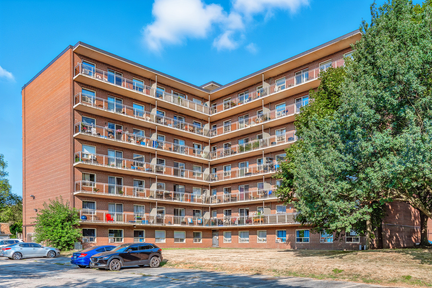 A large apartment building with a blue car parked in front.