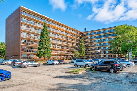 A parking lot with cars and a large building in the background.