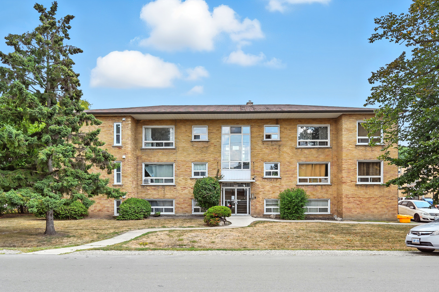 A brick apartment building with a tree in front.