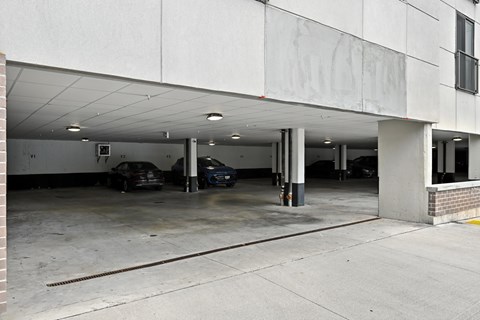 A parking garage with two cars parked in it.