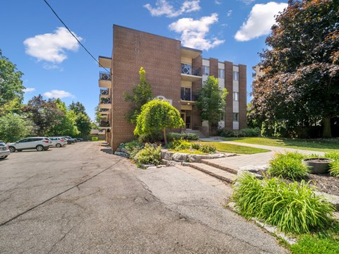 A parking lot in front of a brick apartment building.