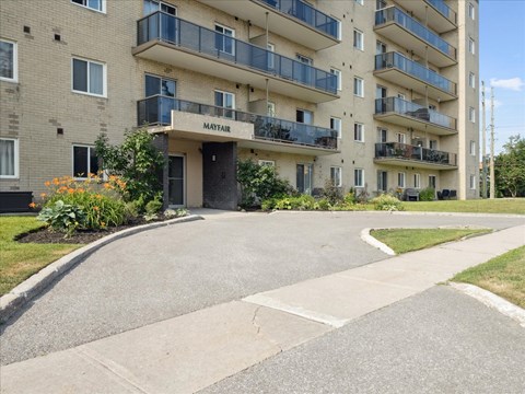 The entrance to the Mayfair apartment complex is surrounded by landscaping.