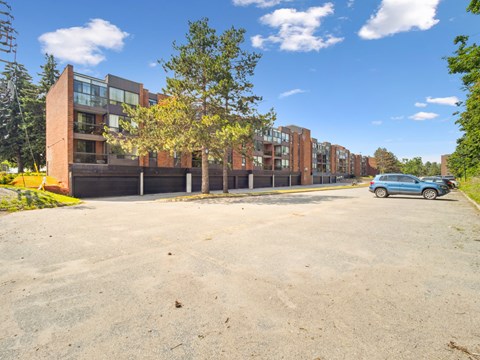 A blue car is parked in a parking lot in front of a building.