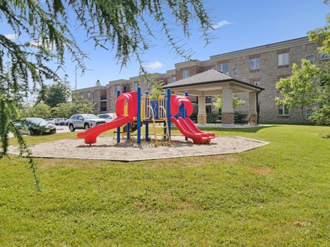 A playground with a red slide in front of a building.