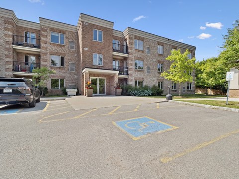 A parking lot in front of a multi-story apartment building with a handicap parking space.