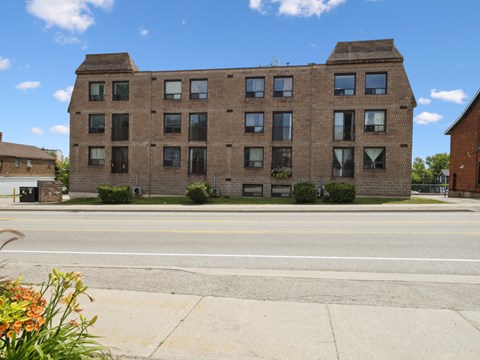A large brick building with many windows sits on a street corner.