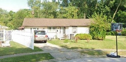 A house with a white fence and a car parked in front.