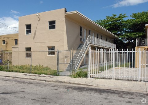 A beige building with a white fence in front.