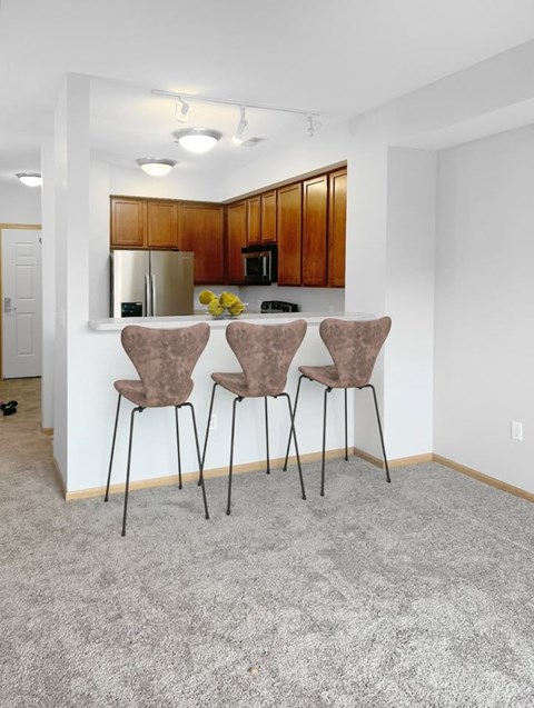 Three brown chairs are placed in a row in a white room.