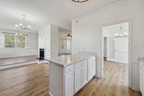A spacious kitchen with white cabinets and a wooden floor.