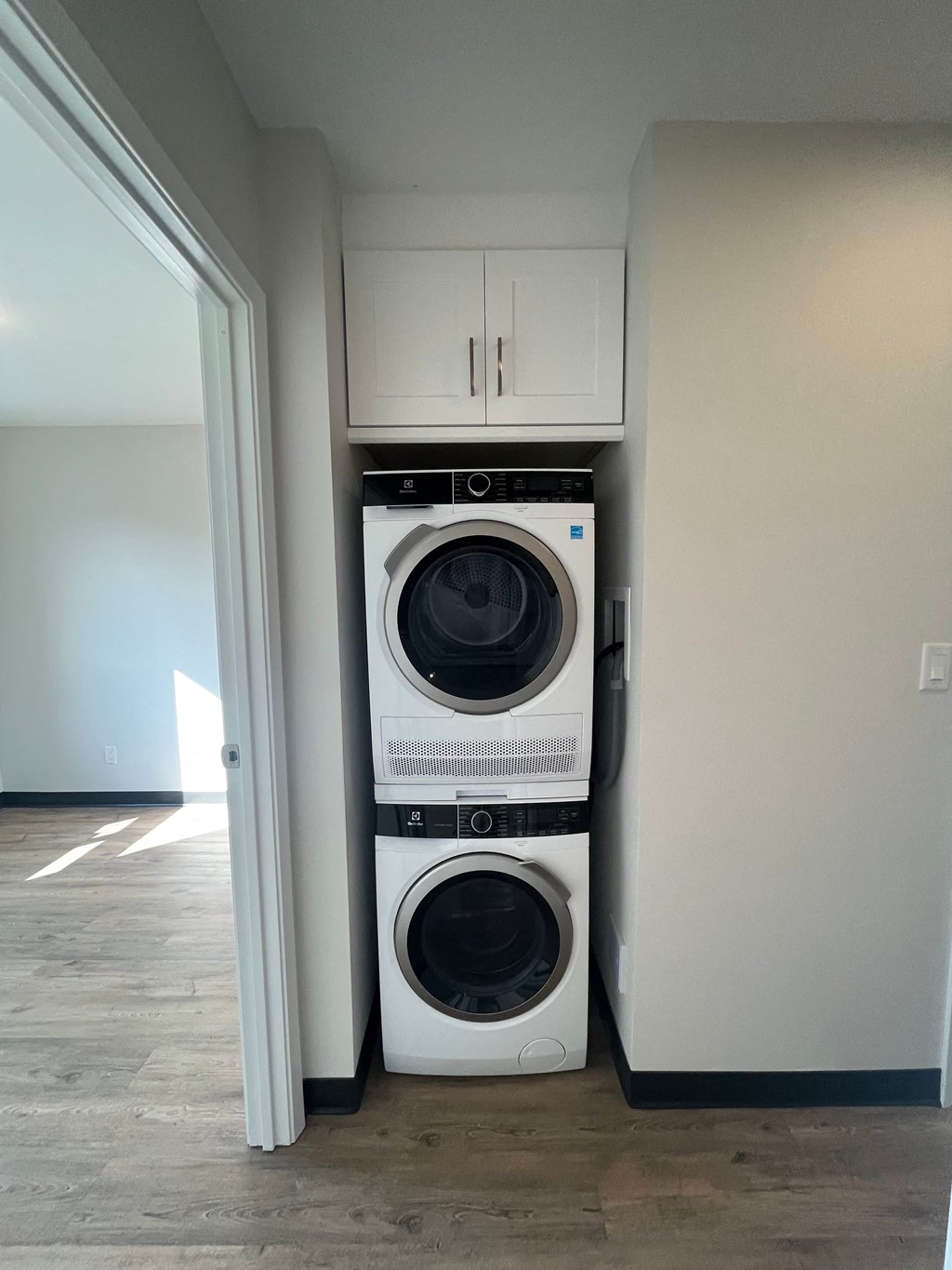 A white dryer and washer are stacked on top of each other in a laundry room.