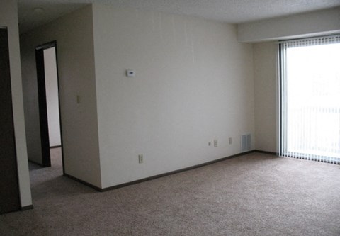 A room with a carpeted floor and a window with blinds.