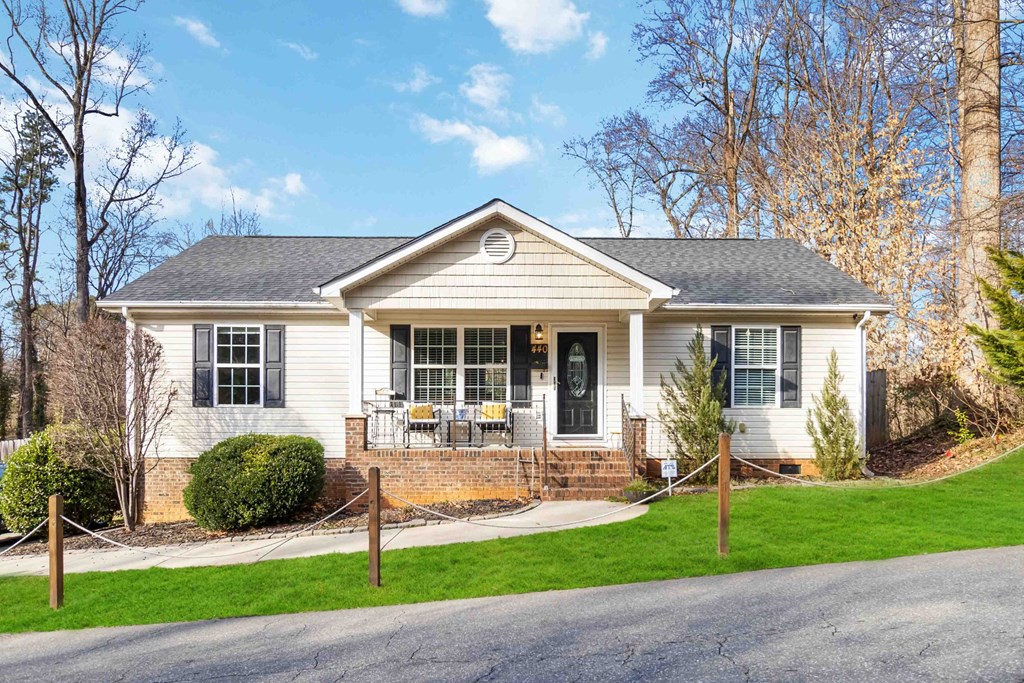 A white house with a black roof and a porch.