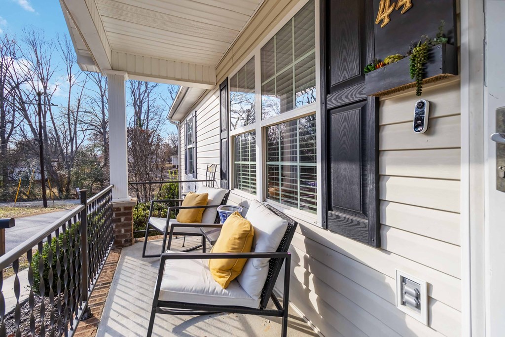 A porch with a white couch and a black metal railing.