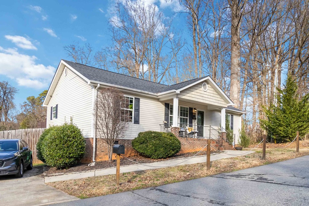 A house with a grey roof and white siding with a mailbox in front.