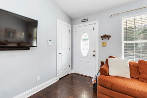 A living room with a brown couch and a flat screen TV mounted on the wall.
