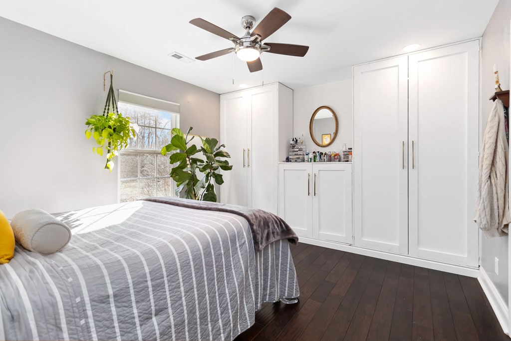 A bedroom with a bed, a ceiling fan, and a window.