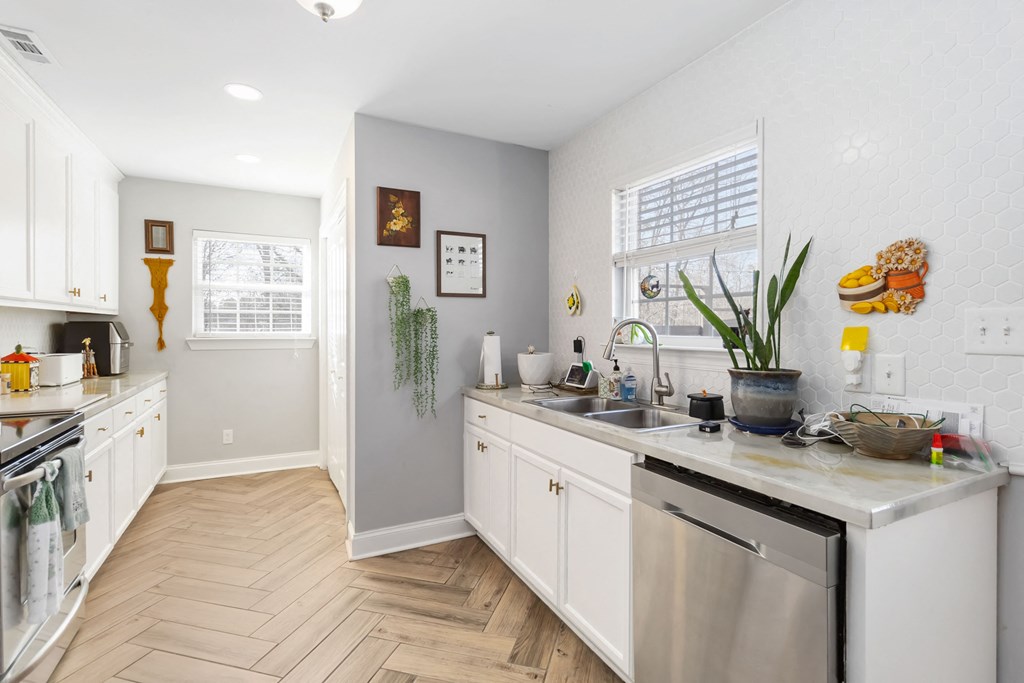 A kitchen with white cabinets and a wooden floor.