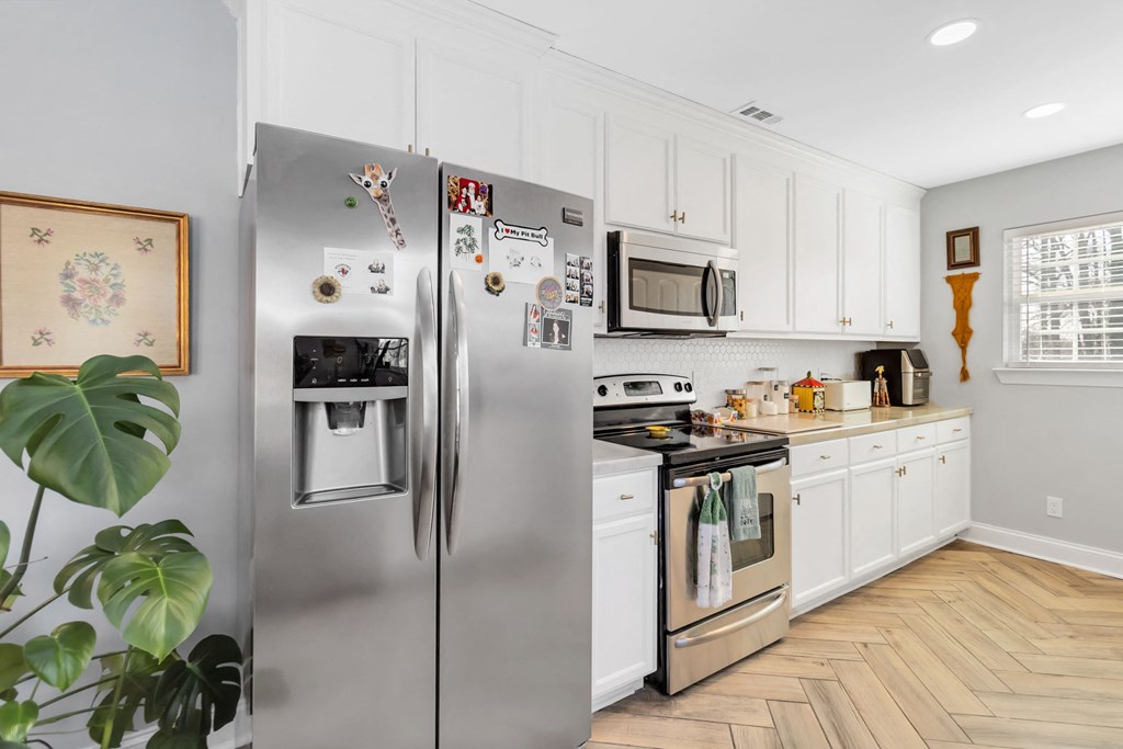 A kitchen with a stainless steel refrigerator and white cabinets.
