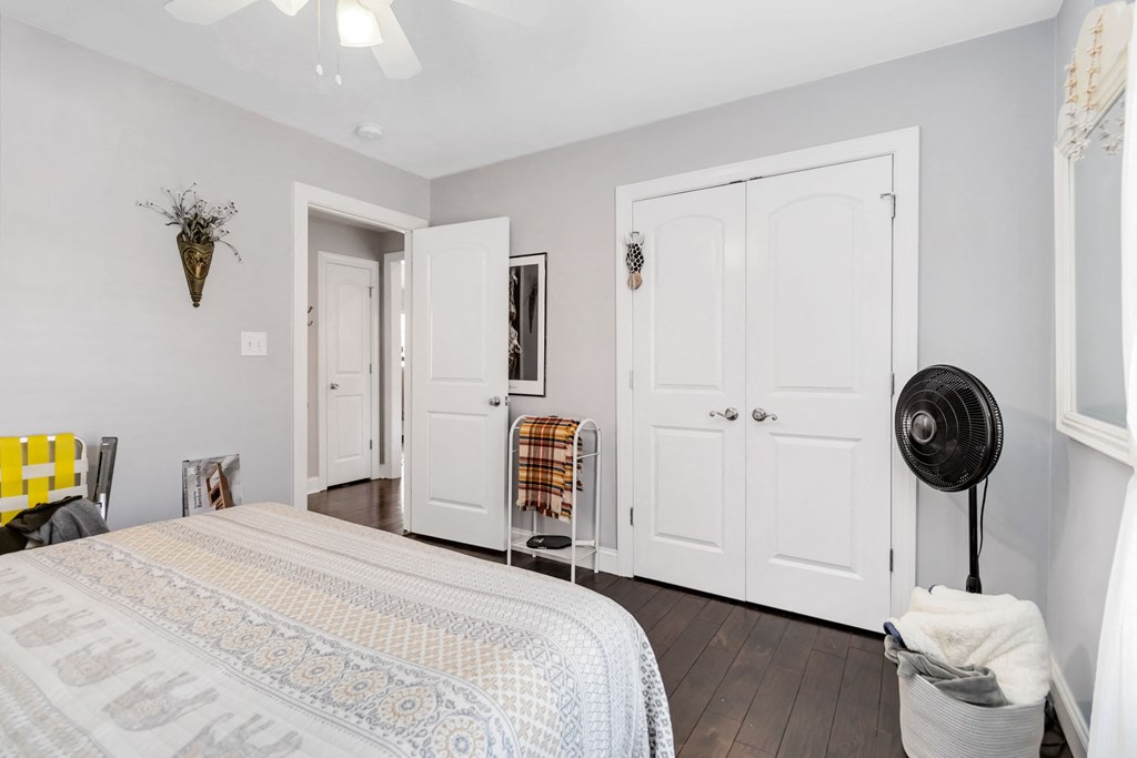 A bedroom with a bed, two doors, and a fan.